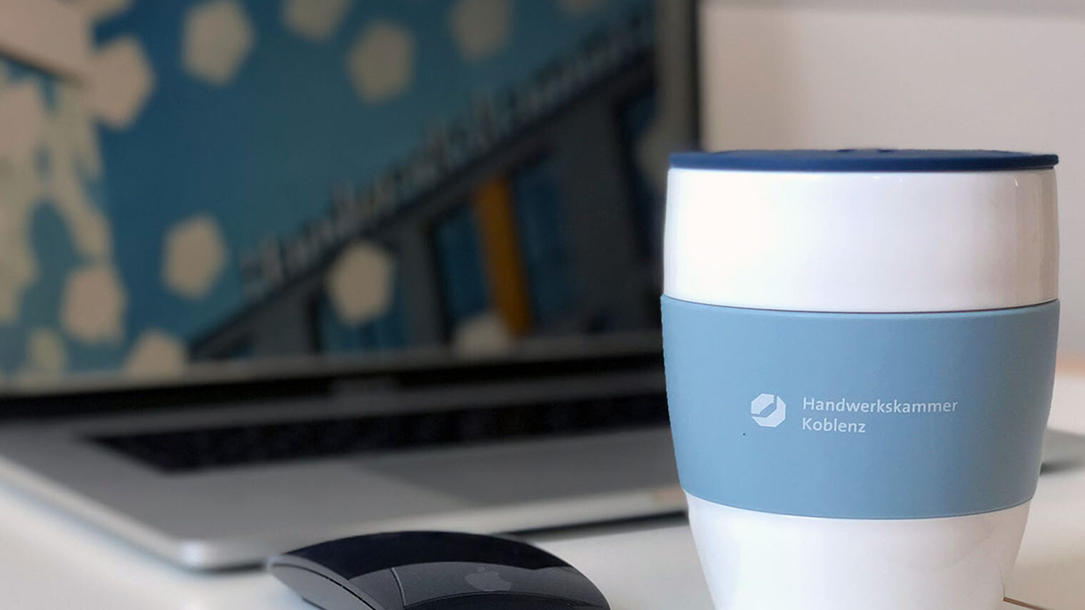 aufgeklappter Laptop und Kaffeebecher