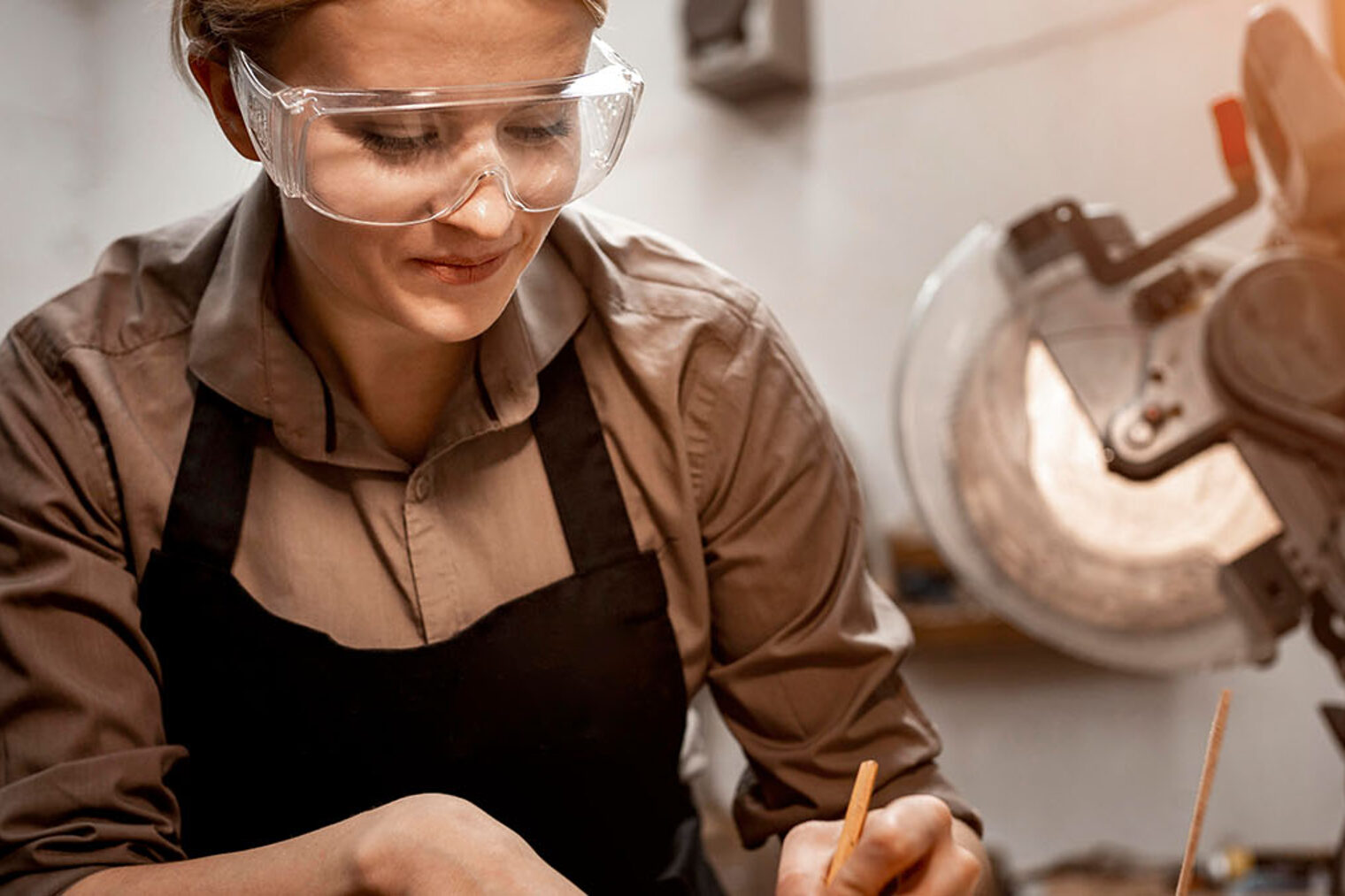 Eine Frau mit Schutzbrille arbeitet an einer Maschine.