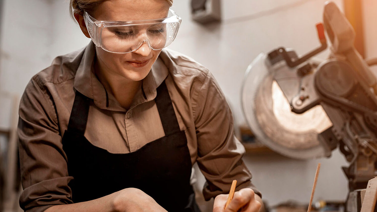 Eine Frau mit Schutzbrille arbeitet an einer Maschine.