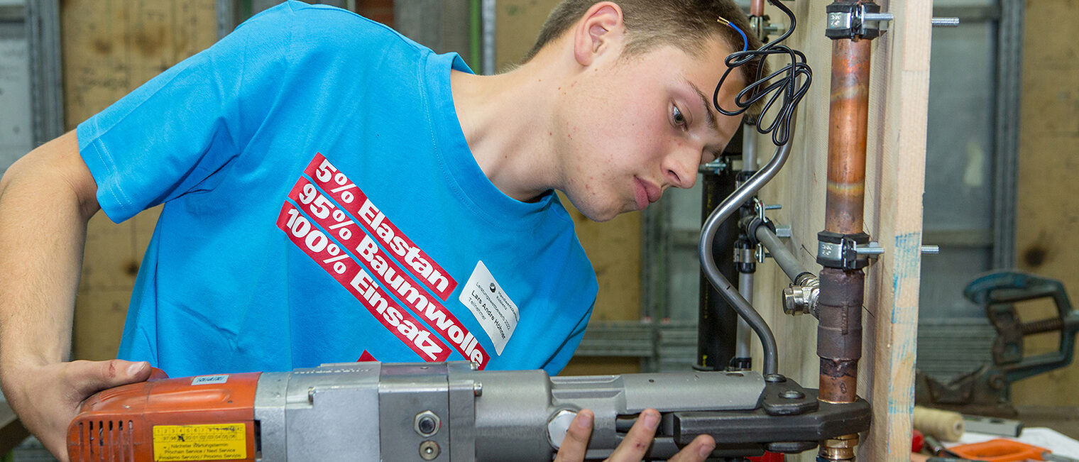 Ein Teilnehmer beim Praktischen Leistungswettbewerb arbeitet mit einer Maschine. Ein Teilnehmer beim Praktischen Leistungswettbewerb arbeitet mit einer Maschine.