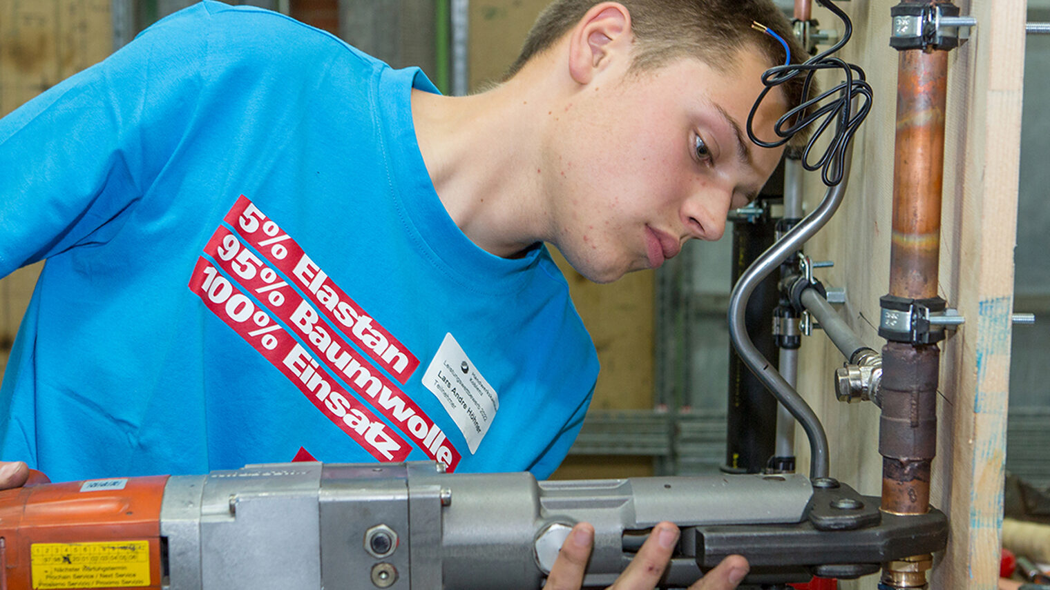 Ein Teilnehmer beim Praktischen Leistungswettbewerb arbeitet mit einer Maschine.