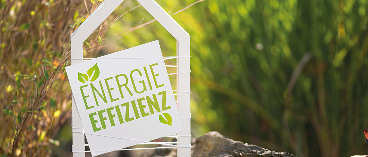 Weißes Haus im Garten mit Schild Energieeffizienz Weißes Haus im Garten mit Schild Energieeffizienz