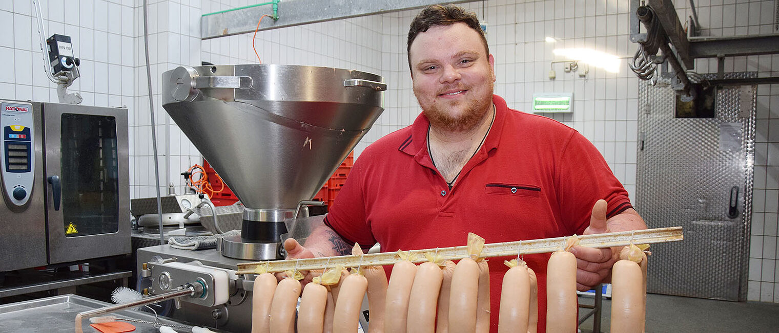 Fleischermeister René Johann zeigt gebrühte Fleischwürste