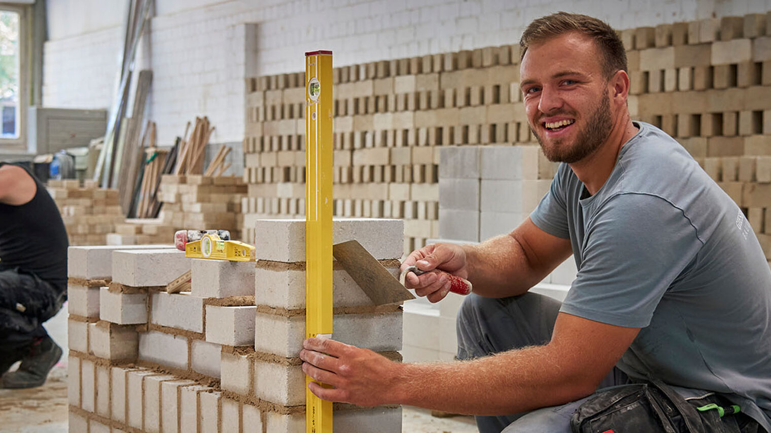 Maurer Mario Thiessen prüft den Aufbau der Mauer mit einer Wasserwaage.