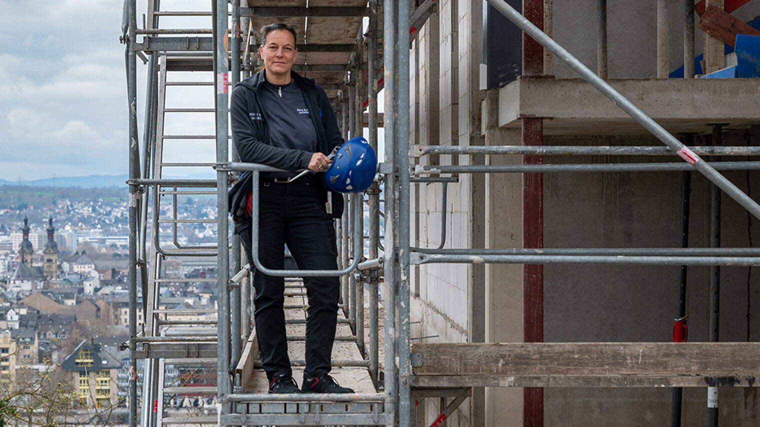 Eine Person steht auf einem Baugerüst