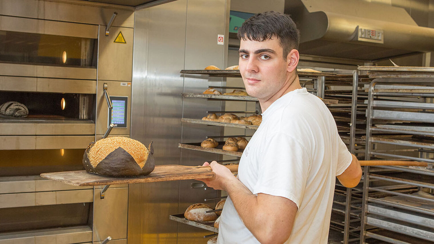 Niklas Ring nimmt ein fertig gebackenes Brot aus dem Ofen.