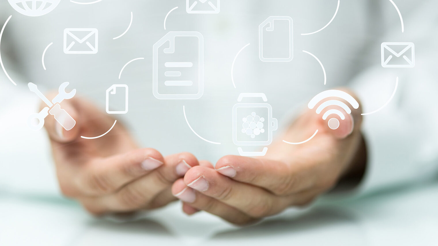 geöffnete Hände und umherfliegende Symbole, wie Werkzeug, Internet, E-Mail