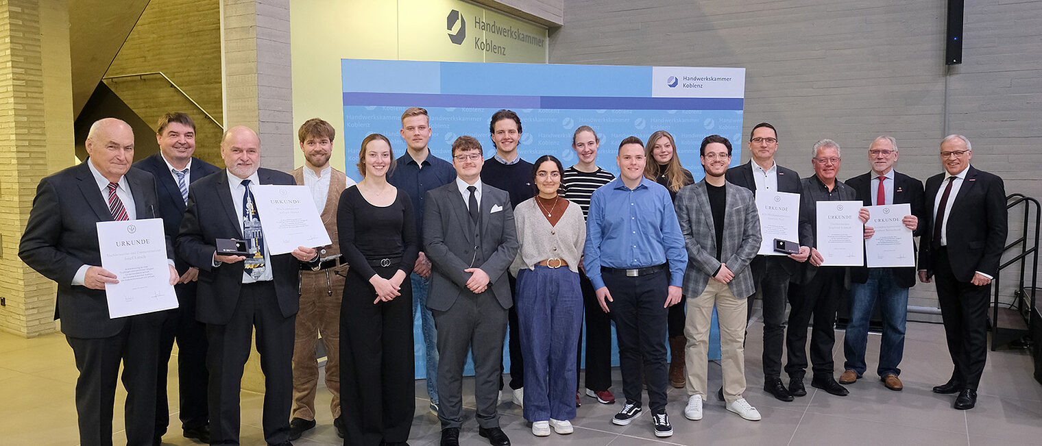 Gruppenfoto der besten Nachwuchshandwerker, eingerahmt durch die Ehrennadelträger und Kurt Krautscheid sowie Bernd Hammes.
