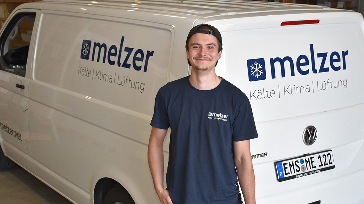 Kreyton Wusch vor einem Auto seines Ausbildungsbetriebes Melzer Kälte Klima Lüftung GmbH