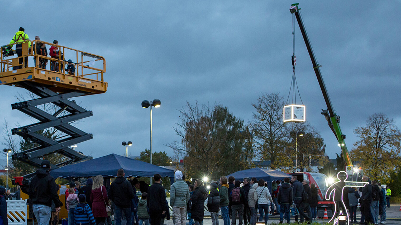 Außenbereich während der Nacht der Technik mit Ständen einiger Aussteller, einem Krahn und einer Hebebühne.