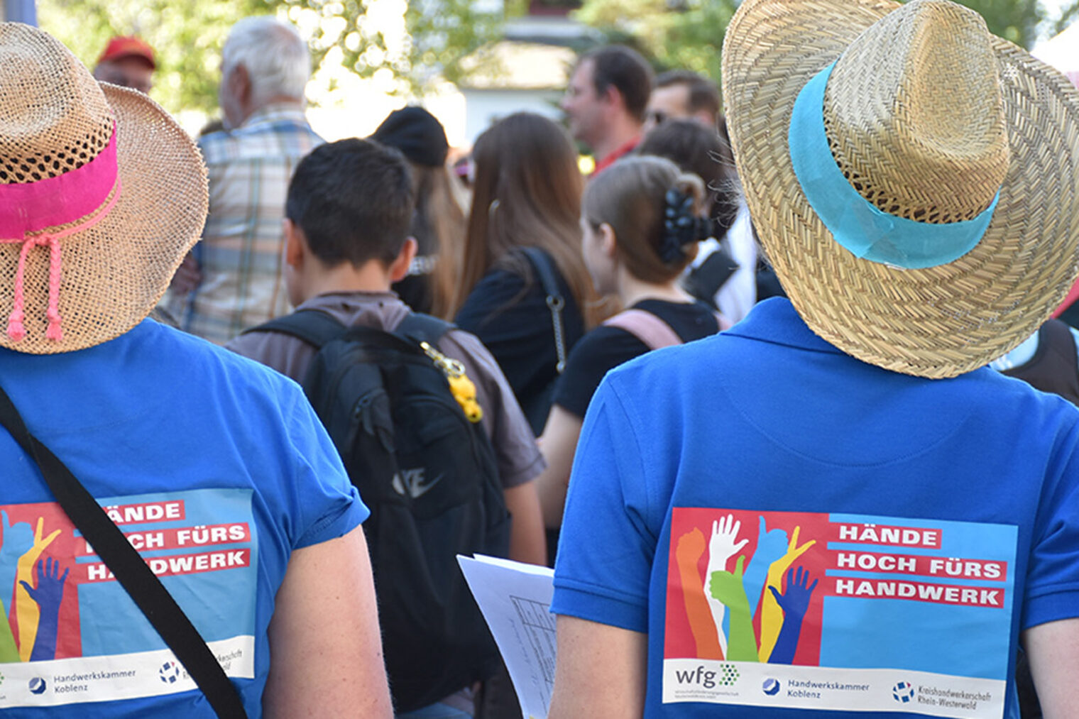 2 Jugendliche, von hinten fotografiert, tragen ein T-Shirt mit der Aufschrift "Hände hoch fürs Handwerk"
