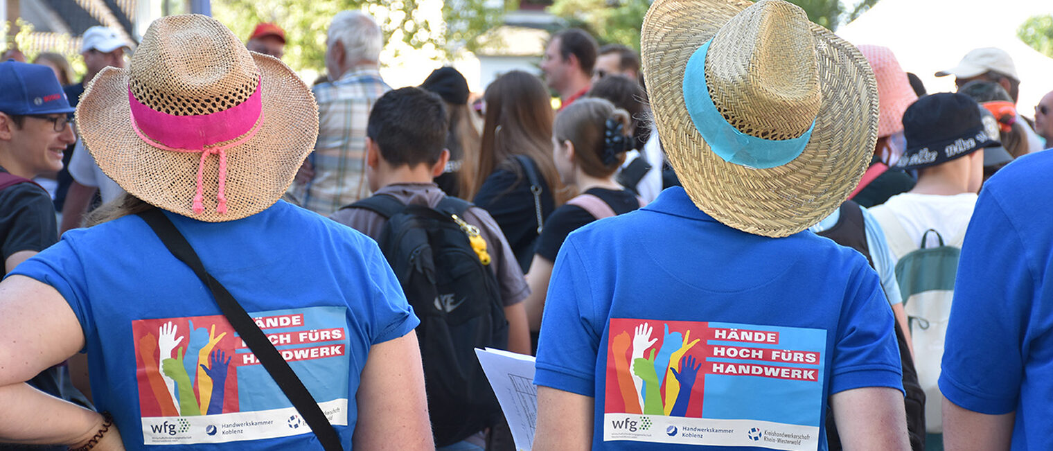 2 Jugendliche, von hinten fotografiert, tragen ein T-Shirt mit der Aufschrift "Hände hoch fürs Handwerk"