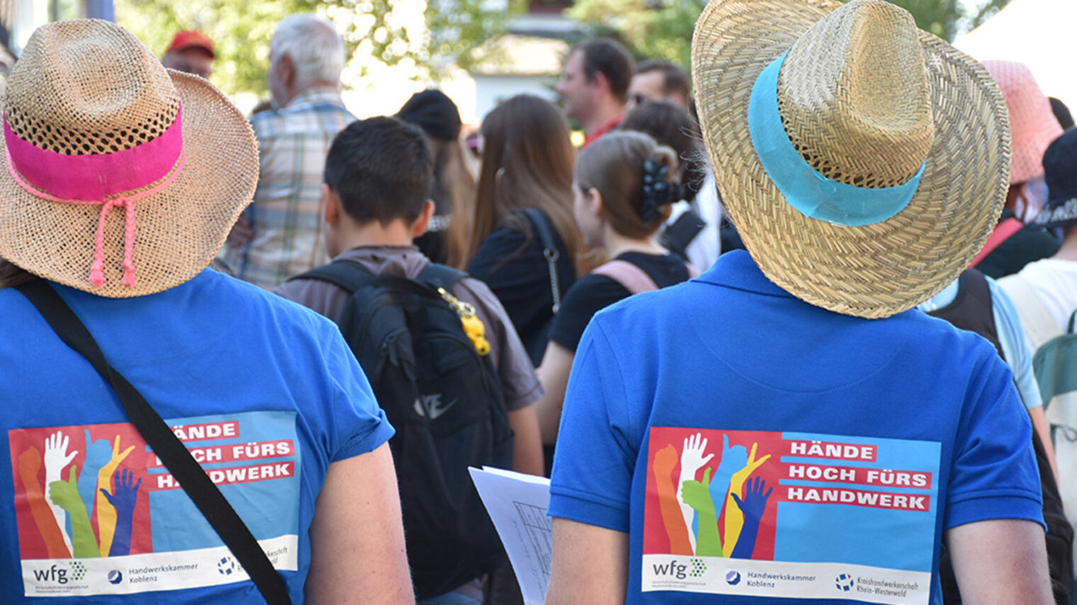 2 Jugendliche, von hinten fotografiert, tragen ein T-Shirt mit der Aufschrift "Hände hoch fürs Handwerk"