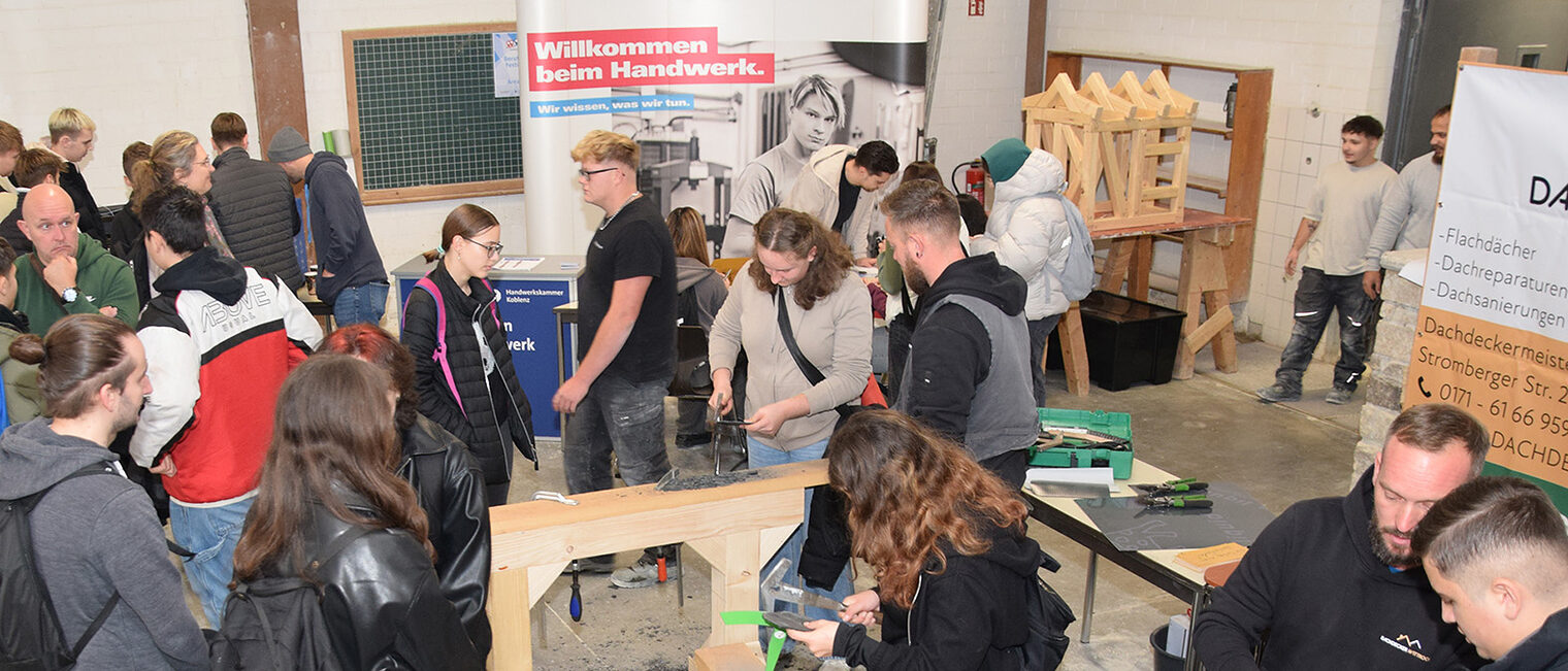 Jugendliche Besucher probieren das Schlagen von Schiefer aus.