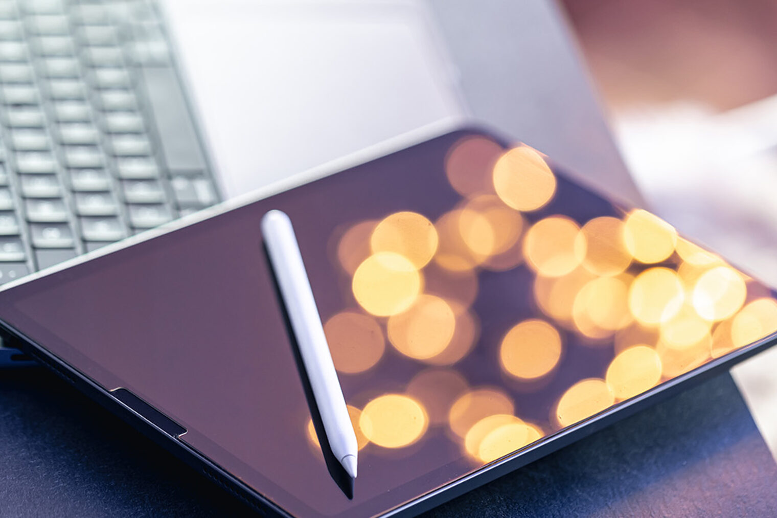 Tablet und Stift auf einem aufgeklappten Laptop