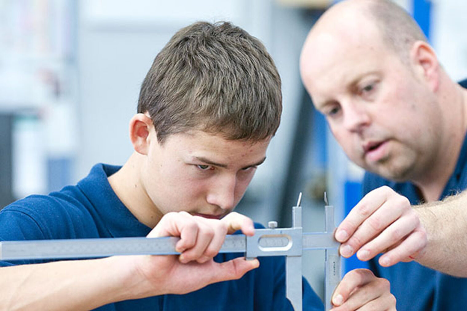 Ausbilder zeigt Lehrling den Umgang mit einer Schieblehre