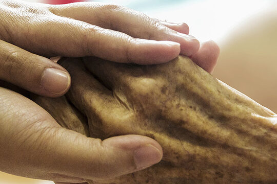 Eine Hand wird von zwei Händen umschlossen.